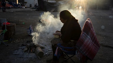 A woman and her husband prepare a fire to cook dinner at Chamizal Park near Bridge of the Americas