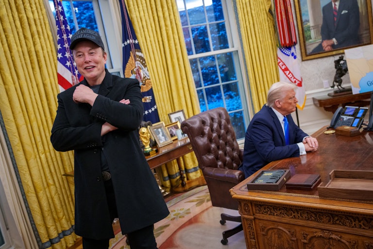 Elon Musk speaks to reporters in the Oval Office while Donald Trump sits at his desk