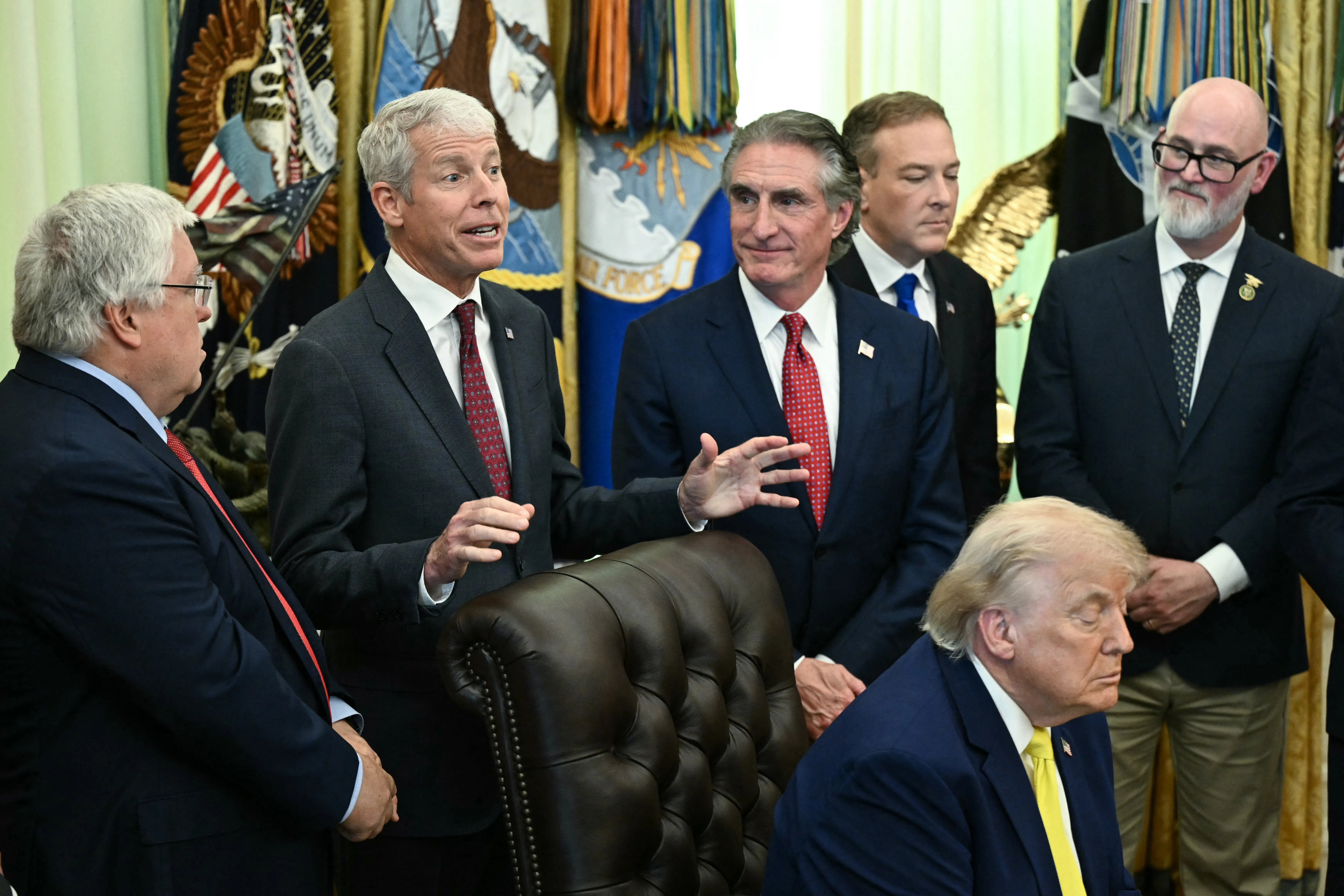 President Donald Trump falls asleep as Secretary of Energy Chris Wright speaks behind him. Others stand around them, including Secretary of the Interior Doug Burgum.