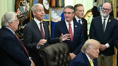 President Donald Trump falls asleep as Secretary of Energy Chris Wright speaks behind him. Others stand around them, including Secretary of the Interior Doug Burgum.