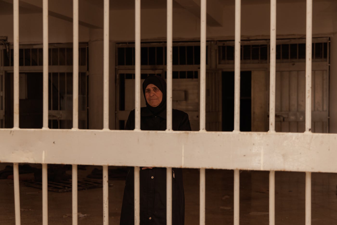 Ms. Samar Saeed, 50, poses for a photo in a common area under the watchful eye of a central tower. 