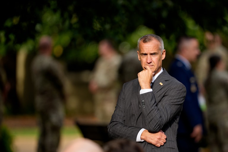 Corey Lewandowski stands with his left hand on his chin and his right hand under his left elbow