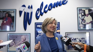 Geoconda Argüello-Kline, Secretary-Treasurer for the Culinary Workers Union stands in a room surrounded by microphones.