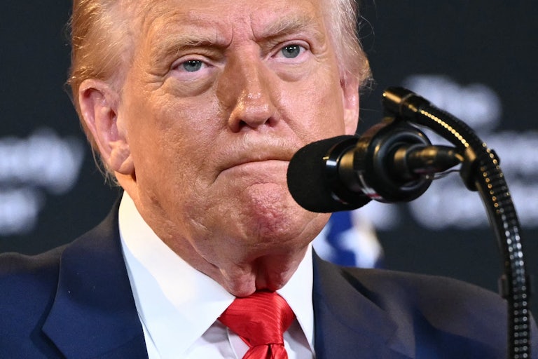 Donald Trump presses his lips together while standing at a microphone