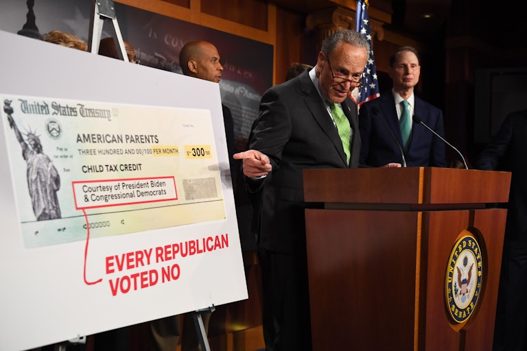 Senate Majority Leader Chuck Schumer points to a sign indicating that Republicans voted against the extension of the child tax credit.