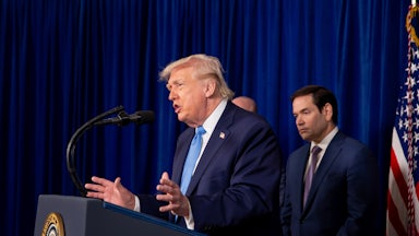 Donald Trump gestures and speaks at a podium while Secretary of State Marco Rubio stands behind him