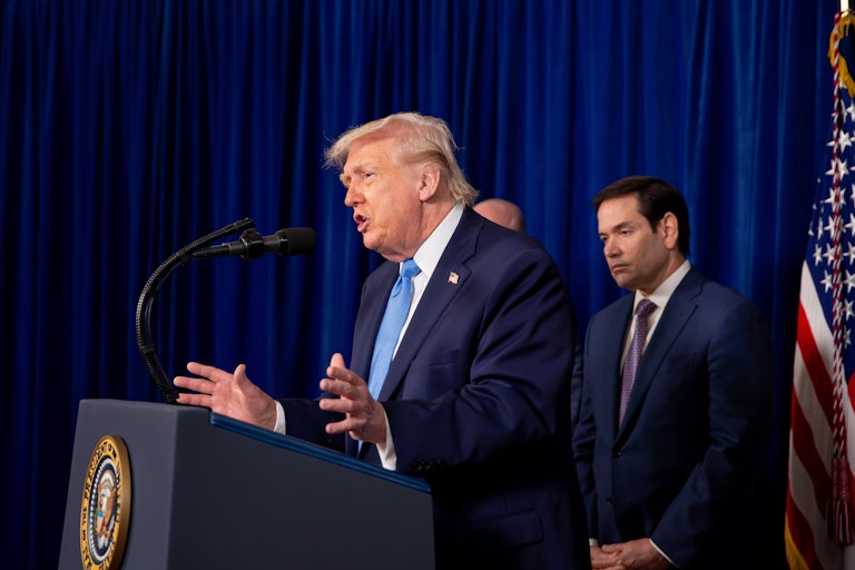 Donald Trump gestures and speaks at a podium while Secretary of State Marco Rubio stands behind him