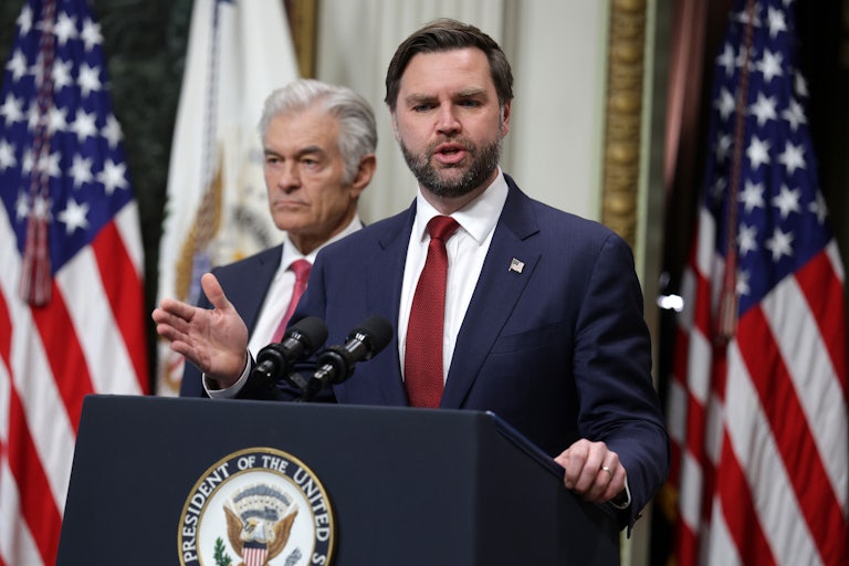 Vice President JD Vance gestures and speaks at a podium. Dr. Oz stands behind him