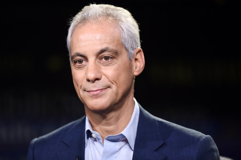 Rahm Emanuel does a toothless smile in front of a black background