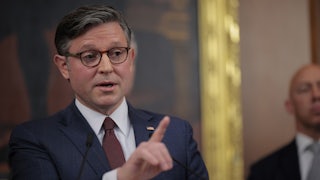 House Speaker Mike Johnson raises a finger while speaking at a podium