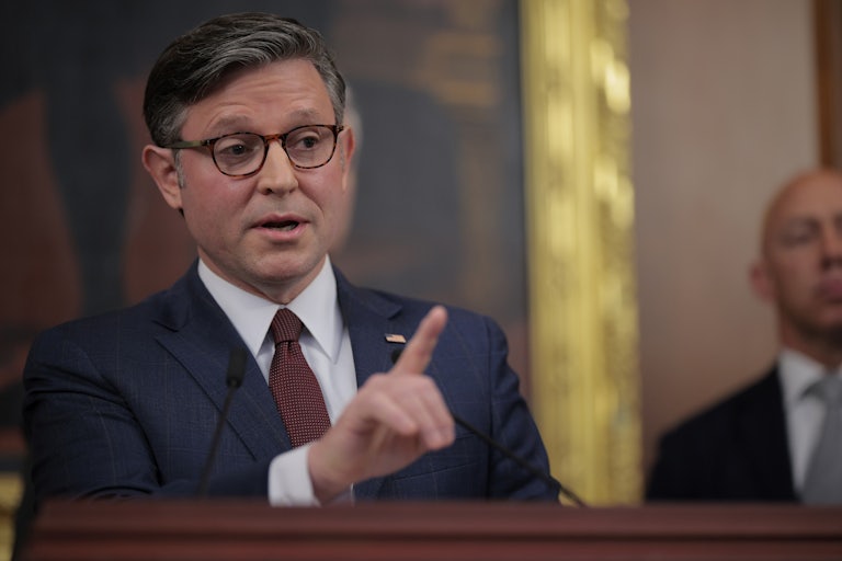 House Speaker Mike Johnson raises a finger while speaking at a podium