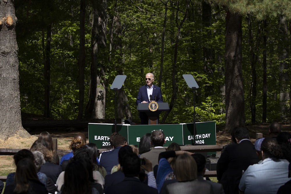President Biden speaks at an "Earth Day 2024" podium in front of trees.
