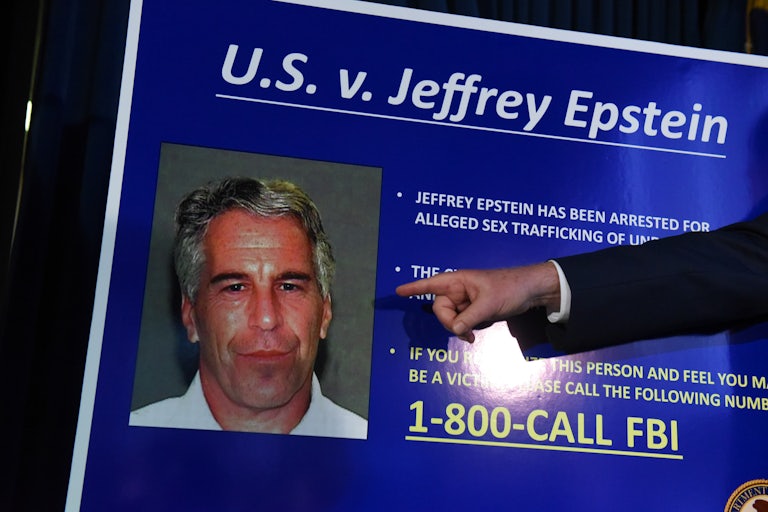 A finger points to Jeffrey Epstein's face on a poster that reads U.S. v Jeffrey Epstein, and lists facts about the case.