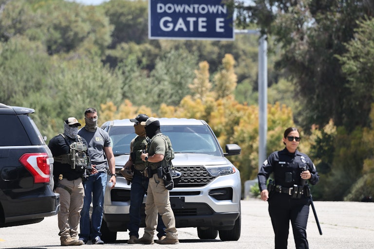 Masked federal agents stand in a parking lot