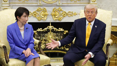 Japanese Prime Minister Sanae Takaichi looks on as Donald Trump speaks and points to her.