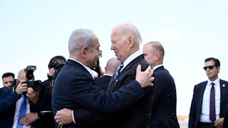 President Joe Biden and Israeli Prime Minister Benjamin Netanyahu hug each other in front of assembled aides and cameramen.