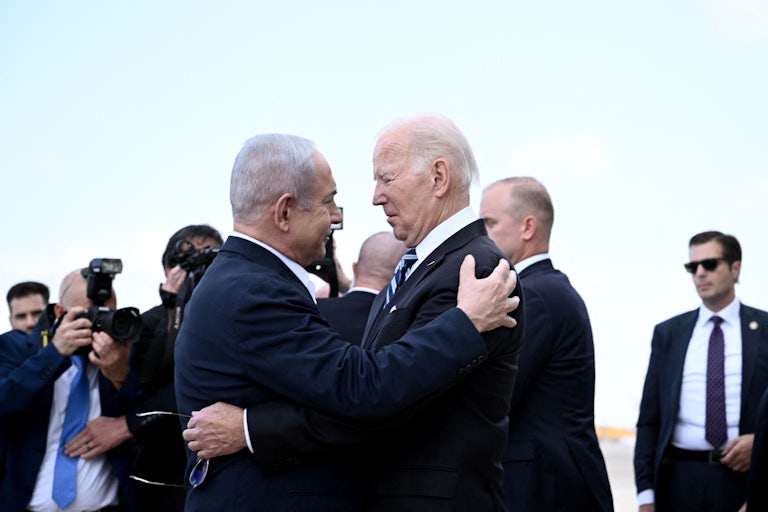 President Joe Biden and Israeli Prime Minister Benjamin Netanyahu hug each other in front of assembled aides and cameramen.