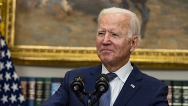 A close-up of Joe Biden, smiling behind a lectern.