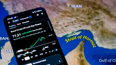 The Brent crude oil price chart from the past week is displayed on a mobile screen, with a map of the Strait of Hormuz in the background