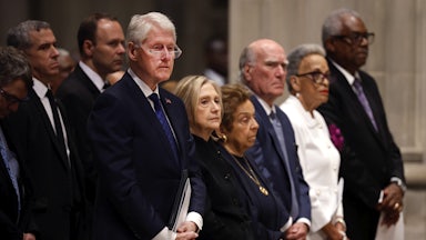 Former U.S. President Bill Clinton and former U.S. Secretary of State Hillary Clinton stand in a pew alongside others.