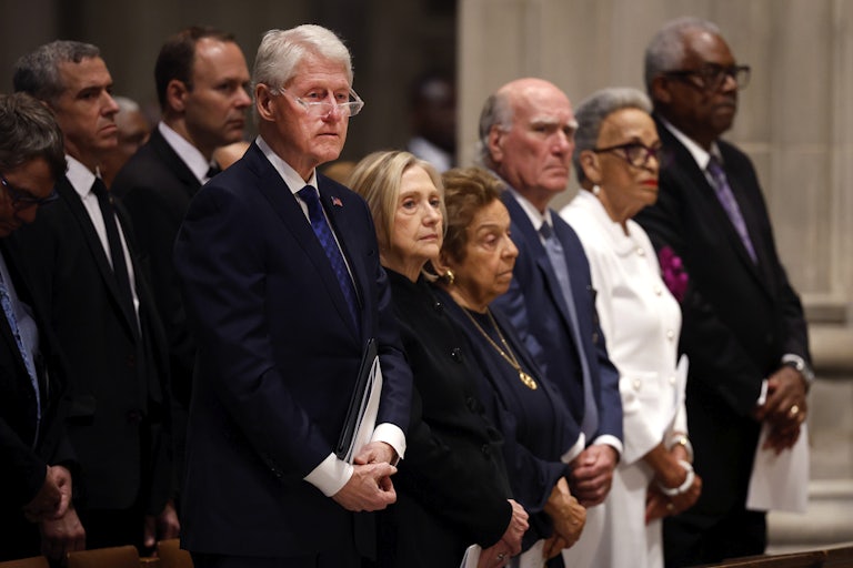 Former U.S. President Bill Clinton and former U.S. Secretary of State Hillary Clinton stand in a pew alongside others.