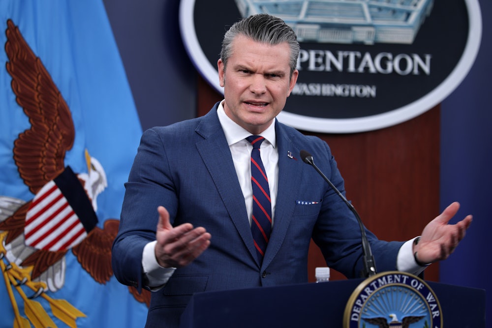 Defense Secretary Pete Hegseth frowns and gestures with both hands while speaking at a podium