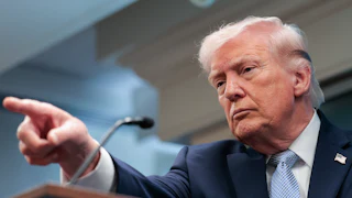 Donald Trump points while standing at a podium