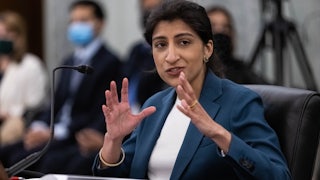 FTC Commissioner Lina M. Khan smiles and gestures with her hands while testifying during a Senate hearing