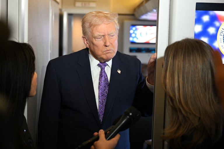 Donald Trump frowns while standing in front of reporters on Air Force One