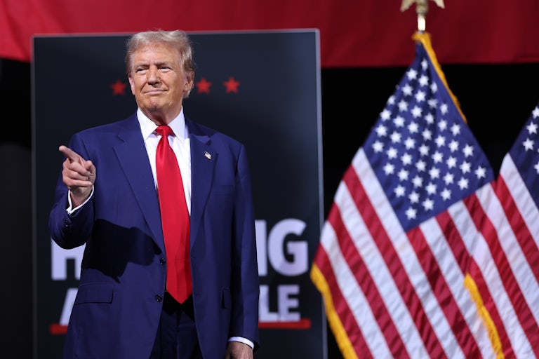 Donald Trump smiles and points to something or someone off screen