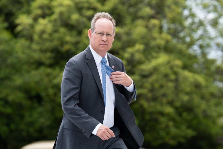 North Carolina Representative Greg Murphy holds his tie as he walks