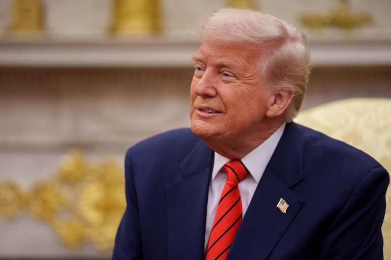 Donald Trump smiles while seated in front of the newly redecorated with gold fireplace in the Oval Office of the White House.