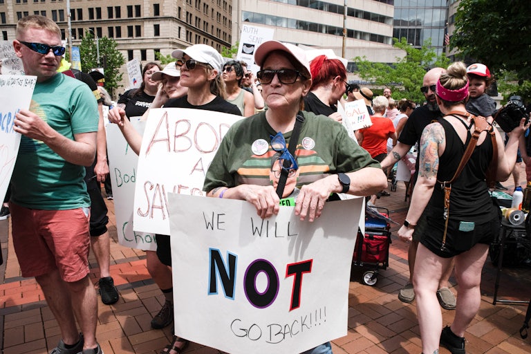 A protester holds a placard that reads "We will not go back" in support of abortion rights, Dayton, Ohio, May 2022. Other protesters stand nearby.