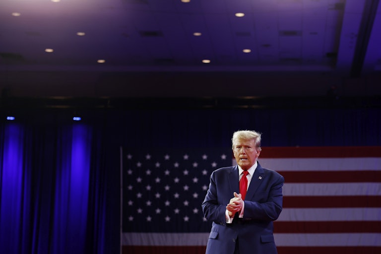Donald Trump stands in front of a large American flag