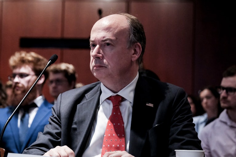 Jeffrey Clark sits at a table during a congressional hearing, a mic in front of him.
