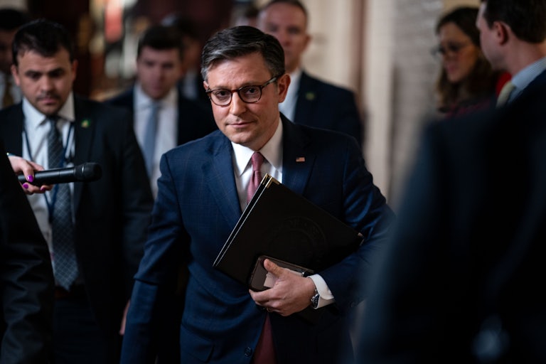 House Speaker Mike Johnson walks down a crowded corridor in the Capitol.