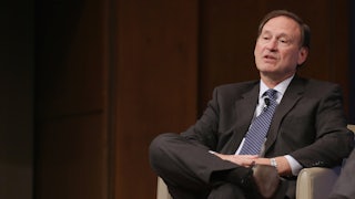 Supreme Court Justice Samuel Alito reclines in a chair.
