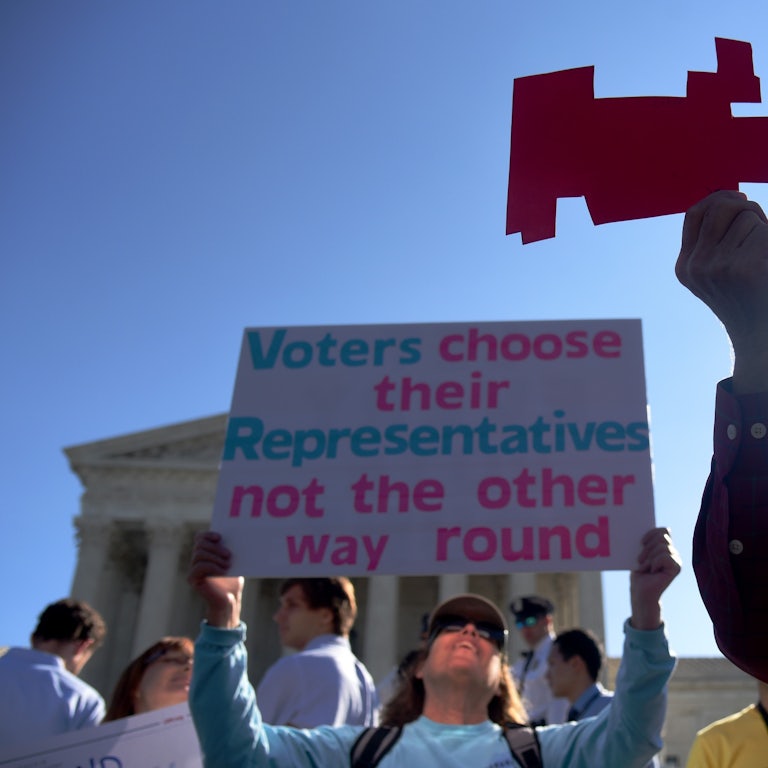 Demonstrators hold a cut out of a gerrymandered district in front of the Supreme Court.