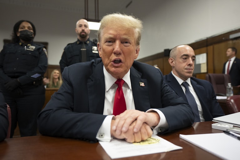 Donald Trump speaks as he sits with his hands folded