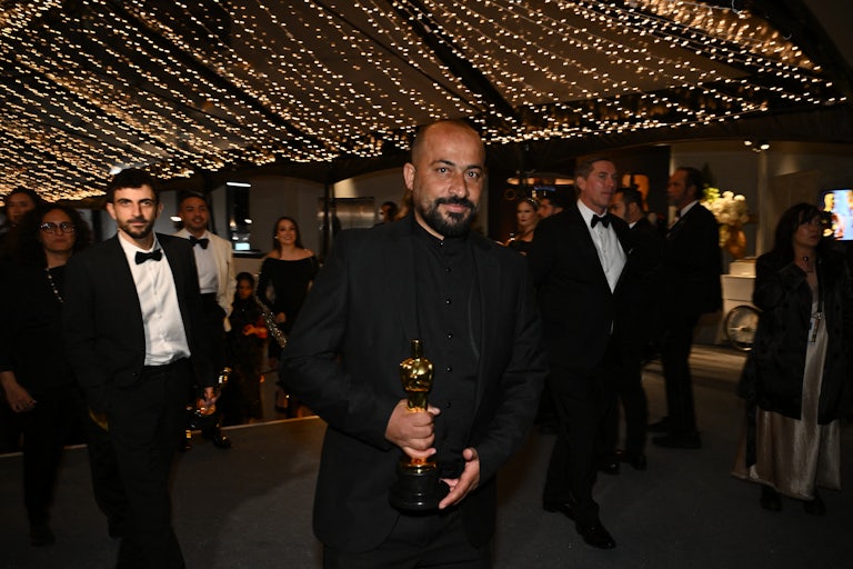 Palestinian director Hamdan Ballal holds his Oscar award at a party.