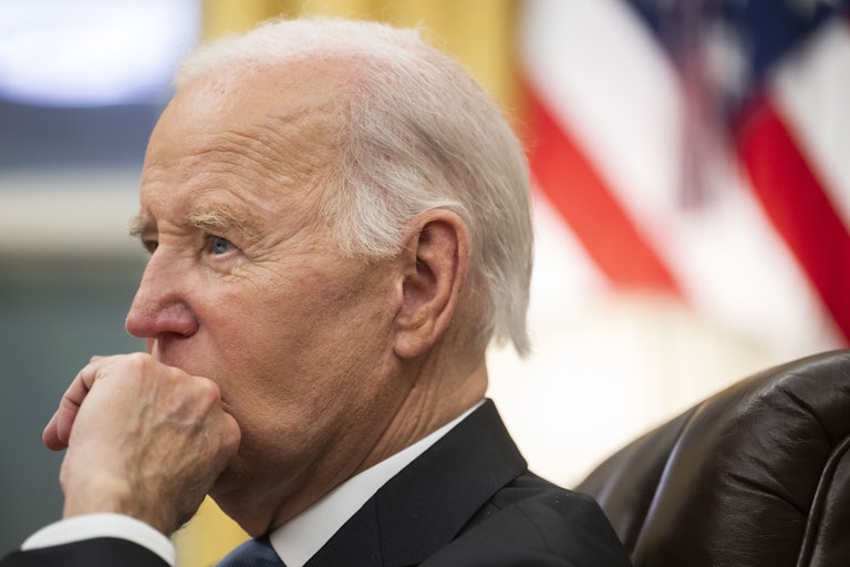 Joe Biden holds his hand up to his mouth