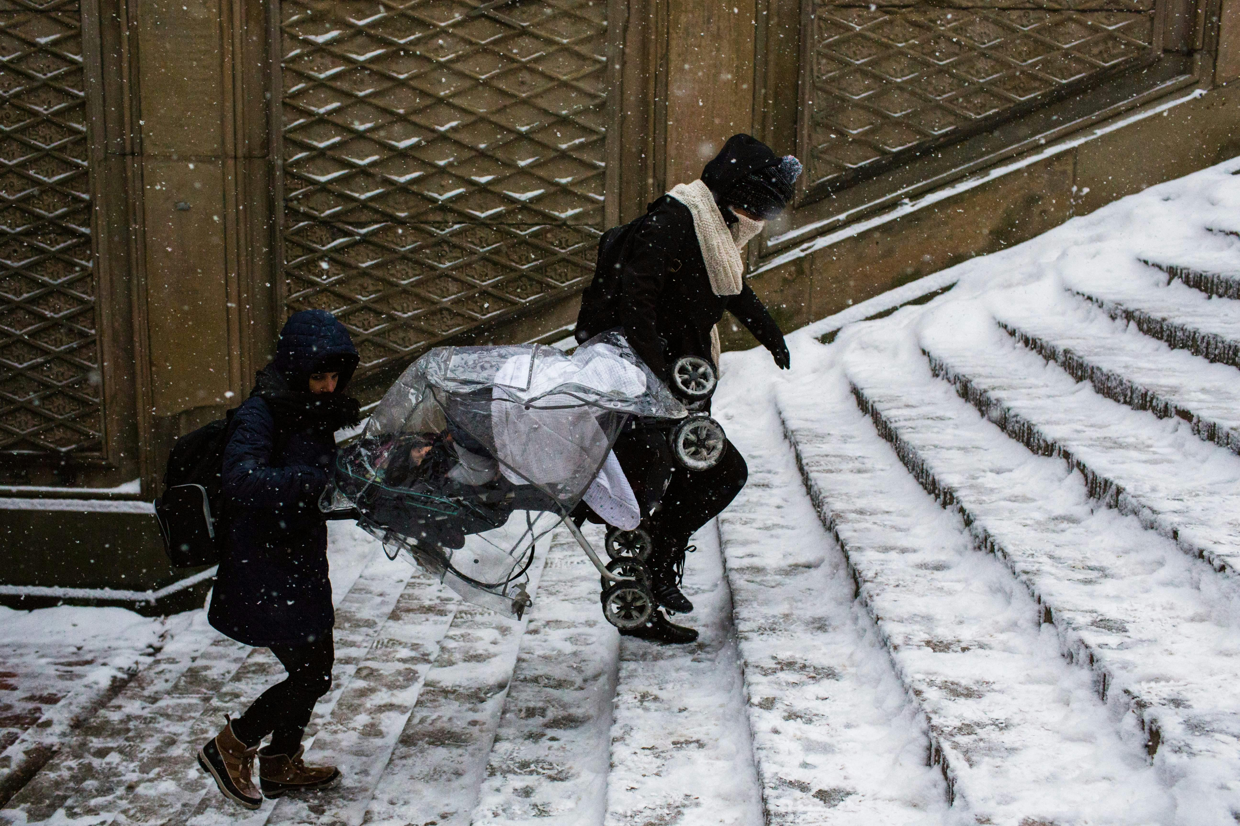 two men carry a stroller up stairs in New York City