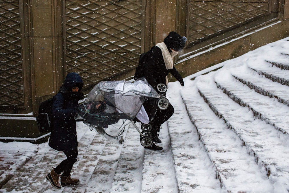 two men carry a stroller up stairs in New York City