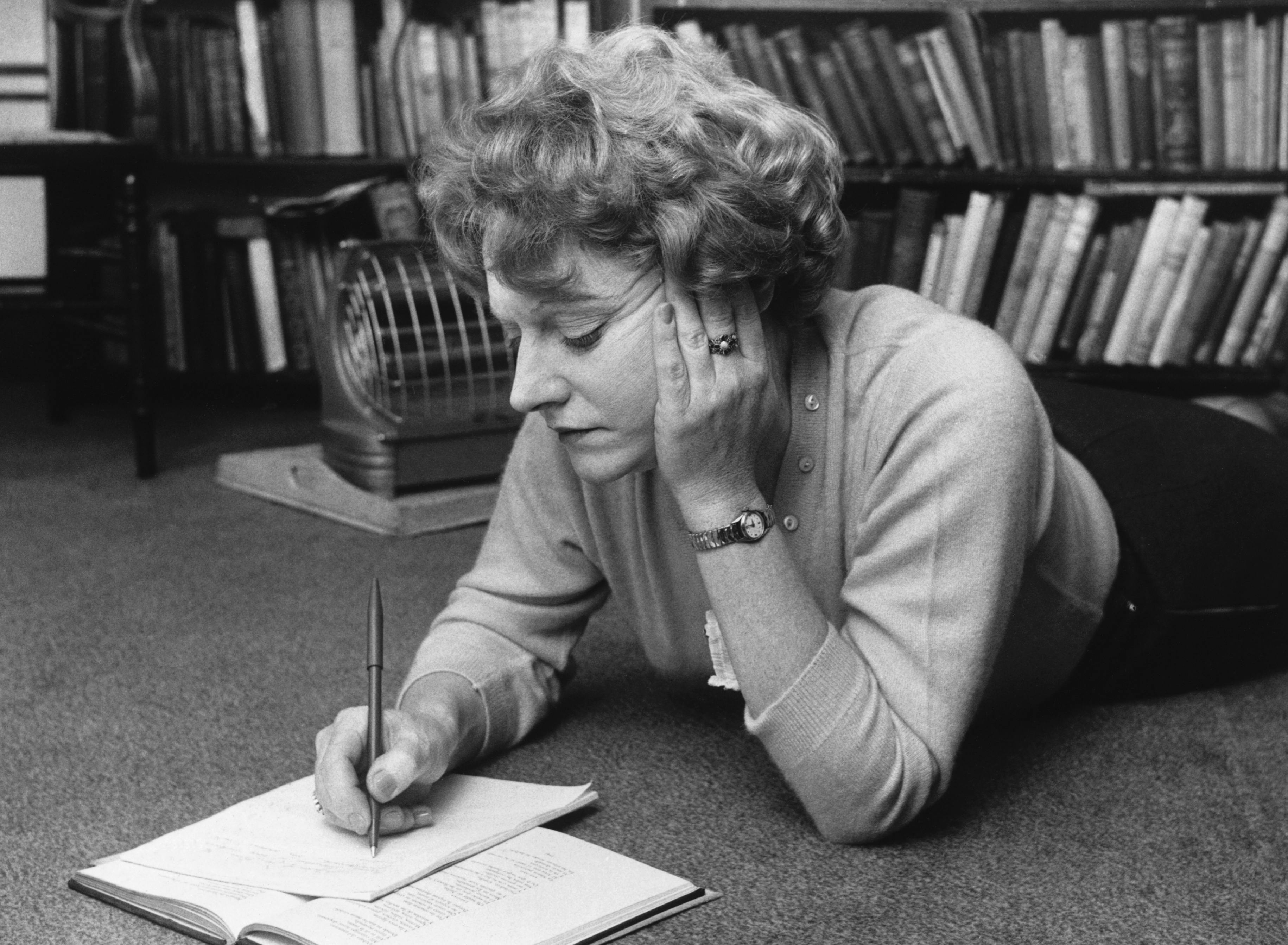 Muriel Spark lying on the floor, writing, in 1960