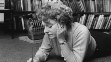 Muriel Spark lying on the floor, writing, in 1960