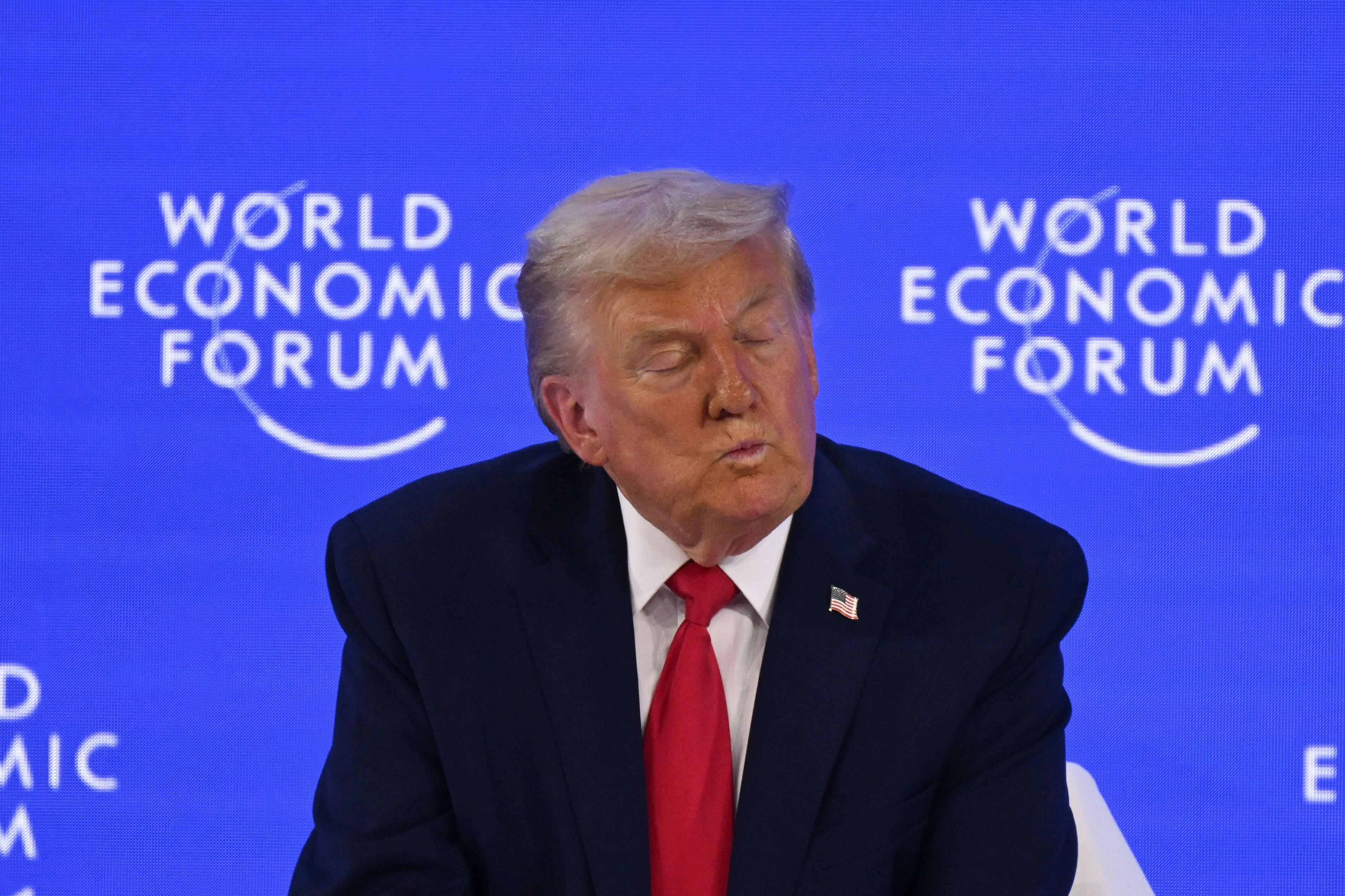 Donald Trump puckers his lips and closes his eyes while sitting on stage at the World Economic Forum in Davos, Switzerland