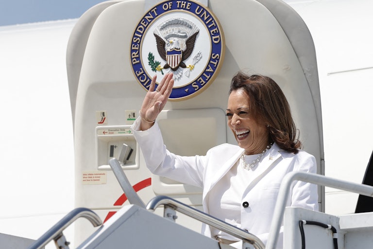 Kamala Harris smiles and waves as she exits her official plane