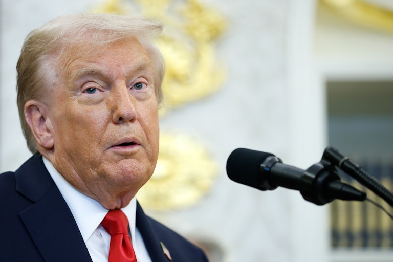 Donald Trump speaks into a microphone in the Oval Office
