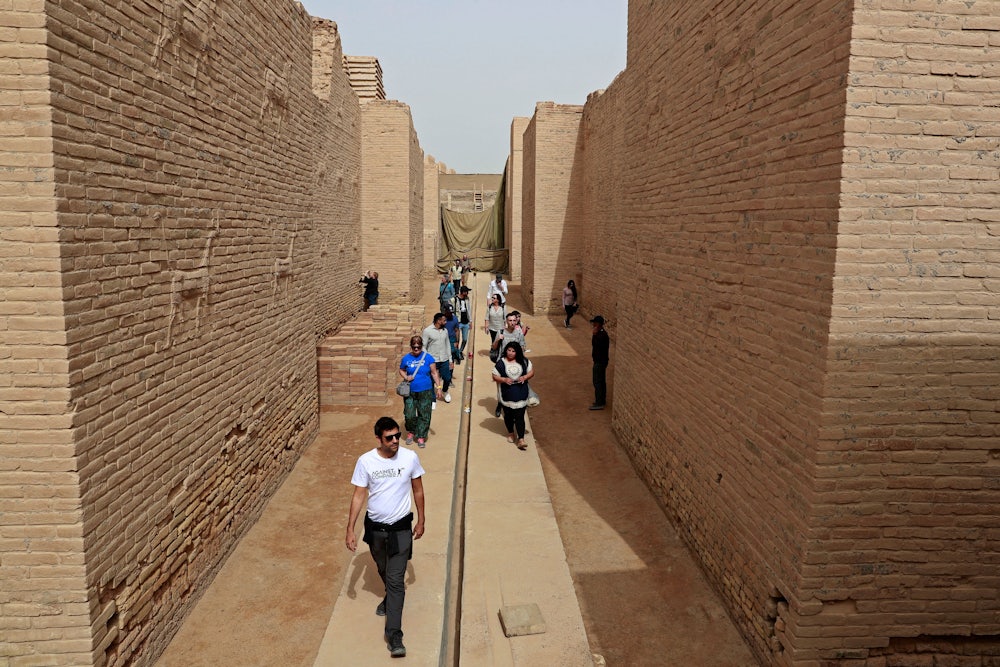 Tourists walk between high stone walls.