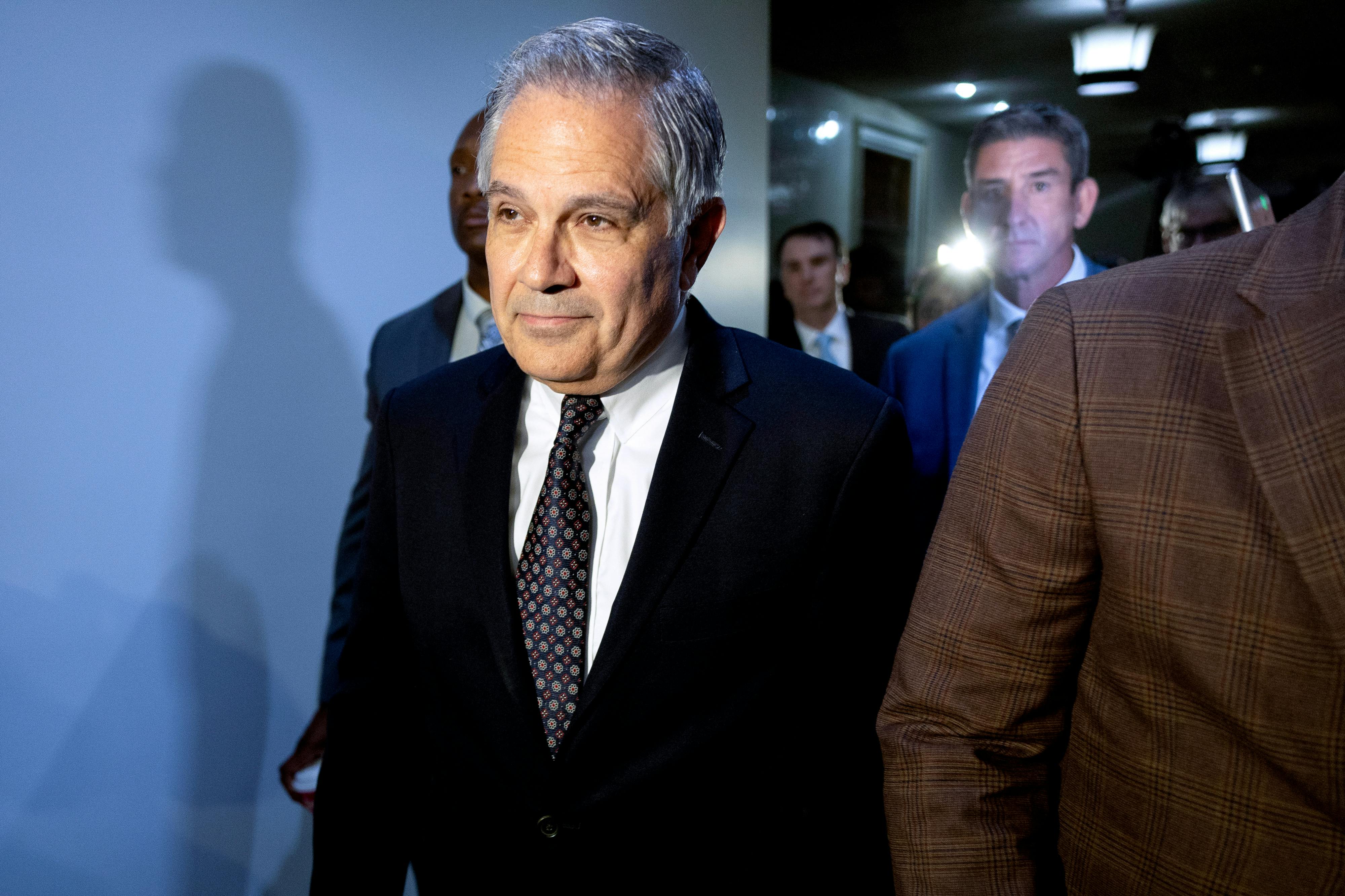 Larry Krasner walks in a hallway and smiles slightly.